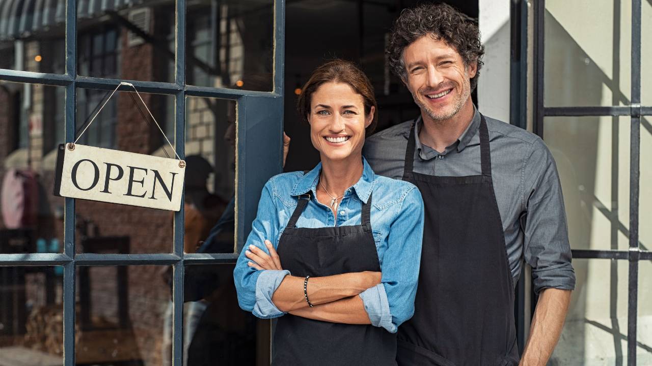 Hombre y mujer emprendedores abriendo las puertas de su negocio