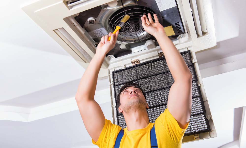 Hombre realizando mantenimiento preventivo a un aire acondicionado en el techo