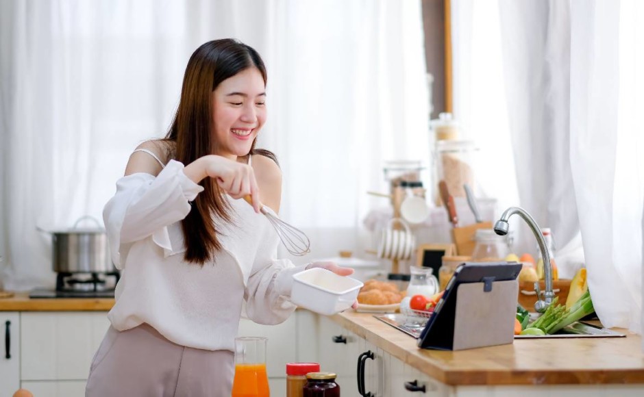 Mujer preparando repostería mientras ve un curso en línea en su tablet