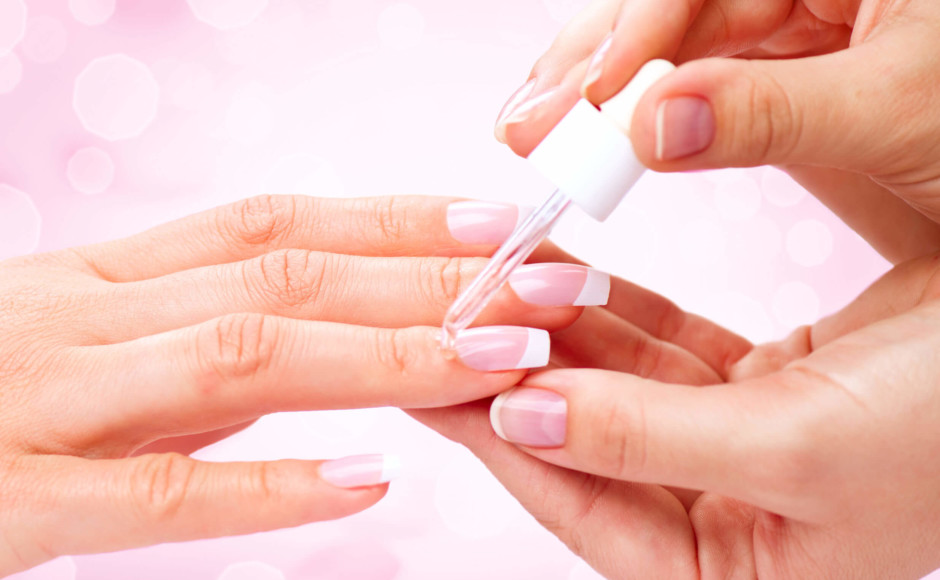 Mãos de uma mulher pintando e cuidando das unhas de outra mulher