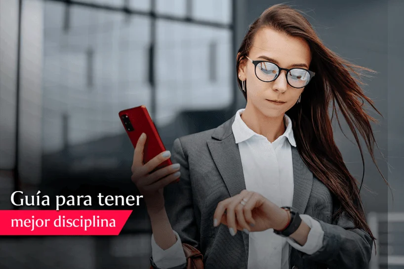 imagen de una mujer en traje viendo su reloj mientras sostiene un teléfono celular