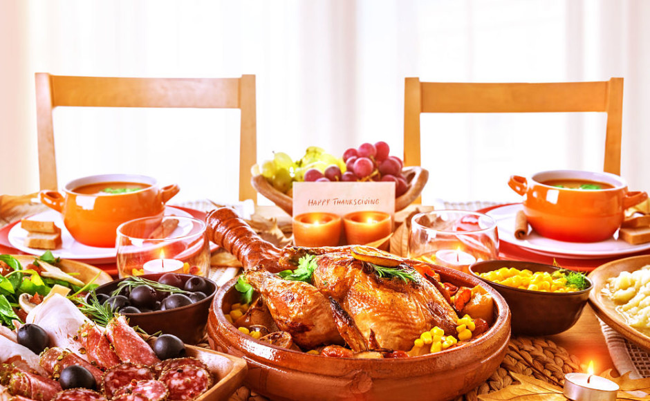 cena de thanksgiving con pavo y diferentes platos con una tarjeta de celebración