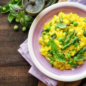 plato con arroz amarillo y esparragos sobre una mesa decorada