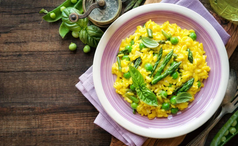 plato con arroz amarillo y esparragos sobre una mesa decorada