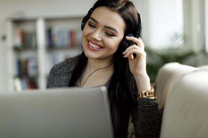 mujer joven sonriendo mientras escucha algo en audifonos