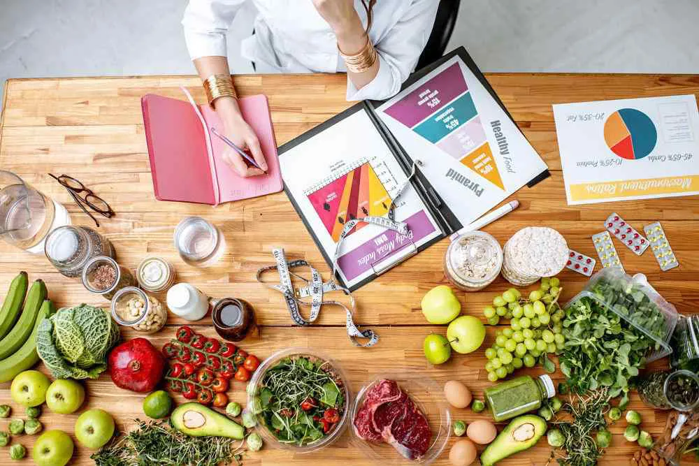 nutricionista escribiendo sobre su borrador con muchas grutas a su alrededor