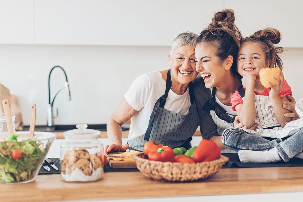 dos mujeres y una niña sonriendo rodeadas de alimentos saludables