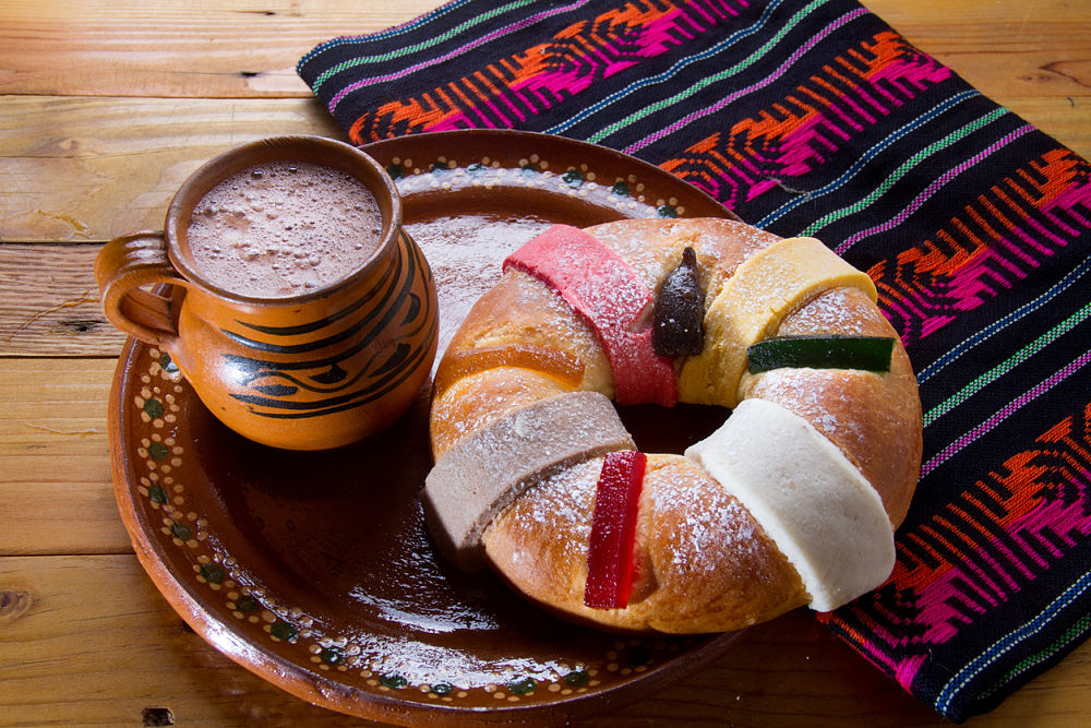 fotografia de una rosca de reyes sobre un plato y una taza de chocolate