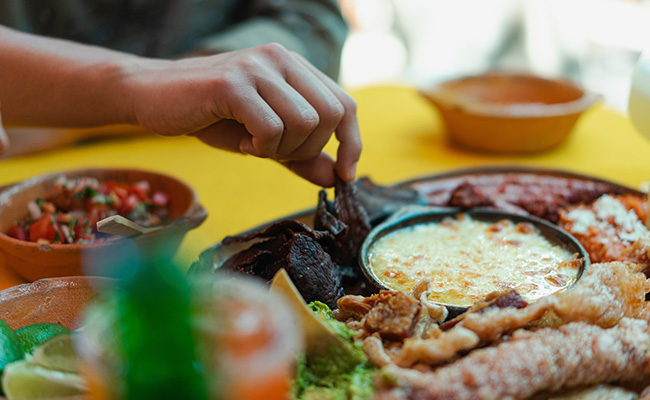 un plato con antojitos mexicanos, nachos, flautas en vaso, tetelas