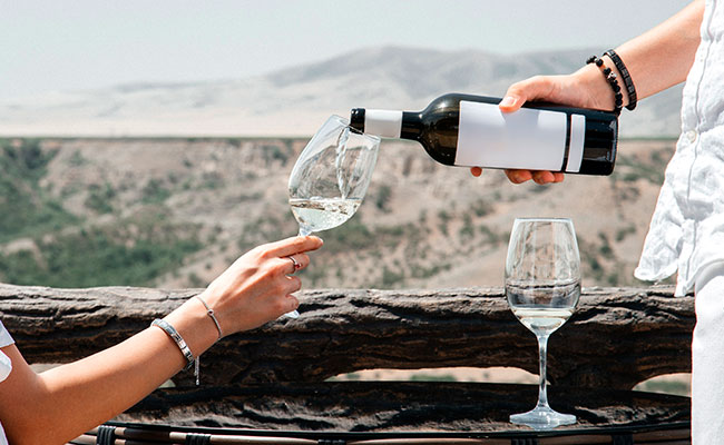 dos personas sosteniendo una copa de vino blanco en una bodega