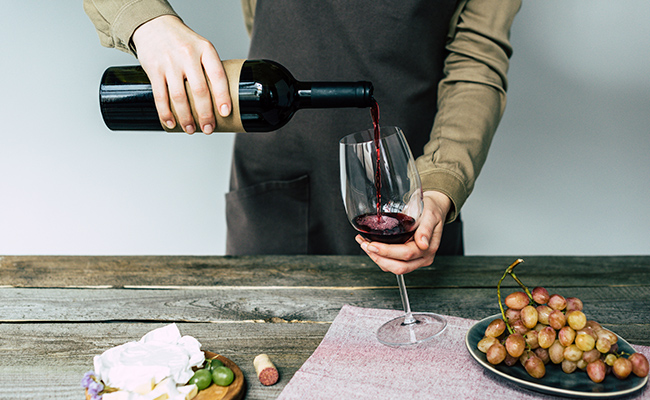 persona sirviendo una botella de vino orgánico