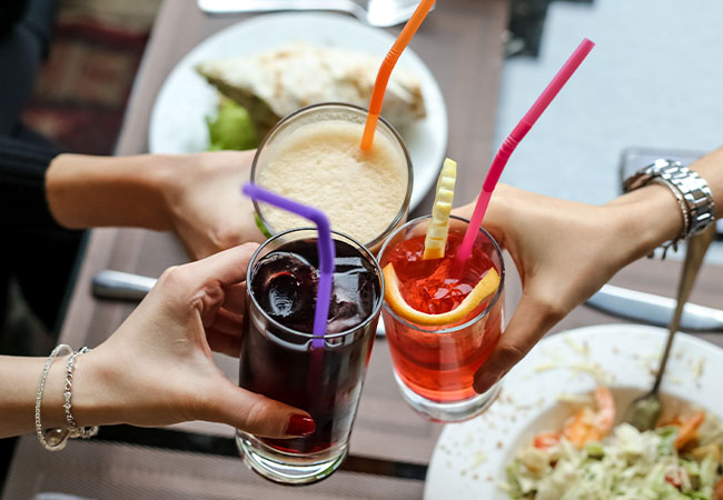 oto de un grupo de amigos compartiendo un almuerzo con copas de aperitivo en sus manos