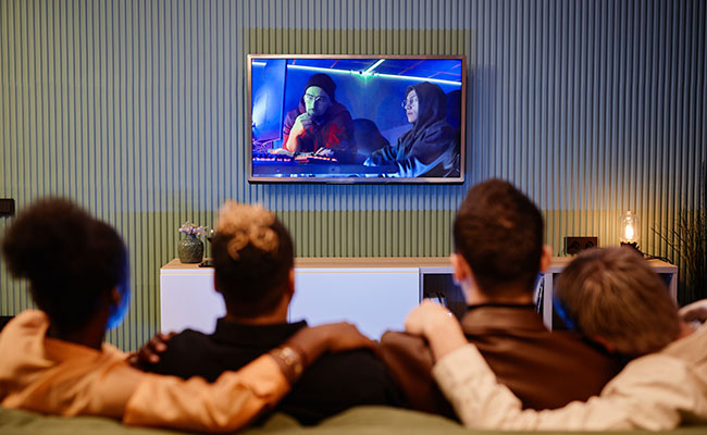 amigos mirando la televisión bajo una lámpara de techo luminosa