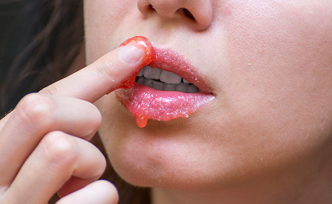  persona aplicándose exfoliante en los labios