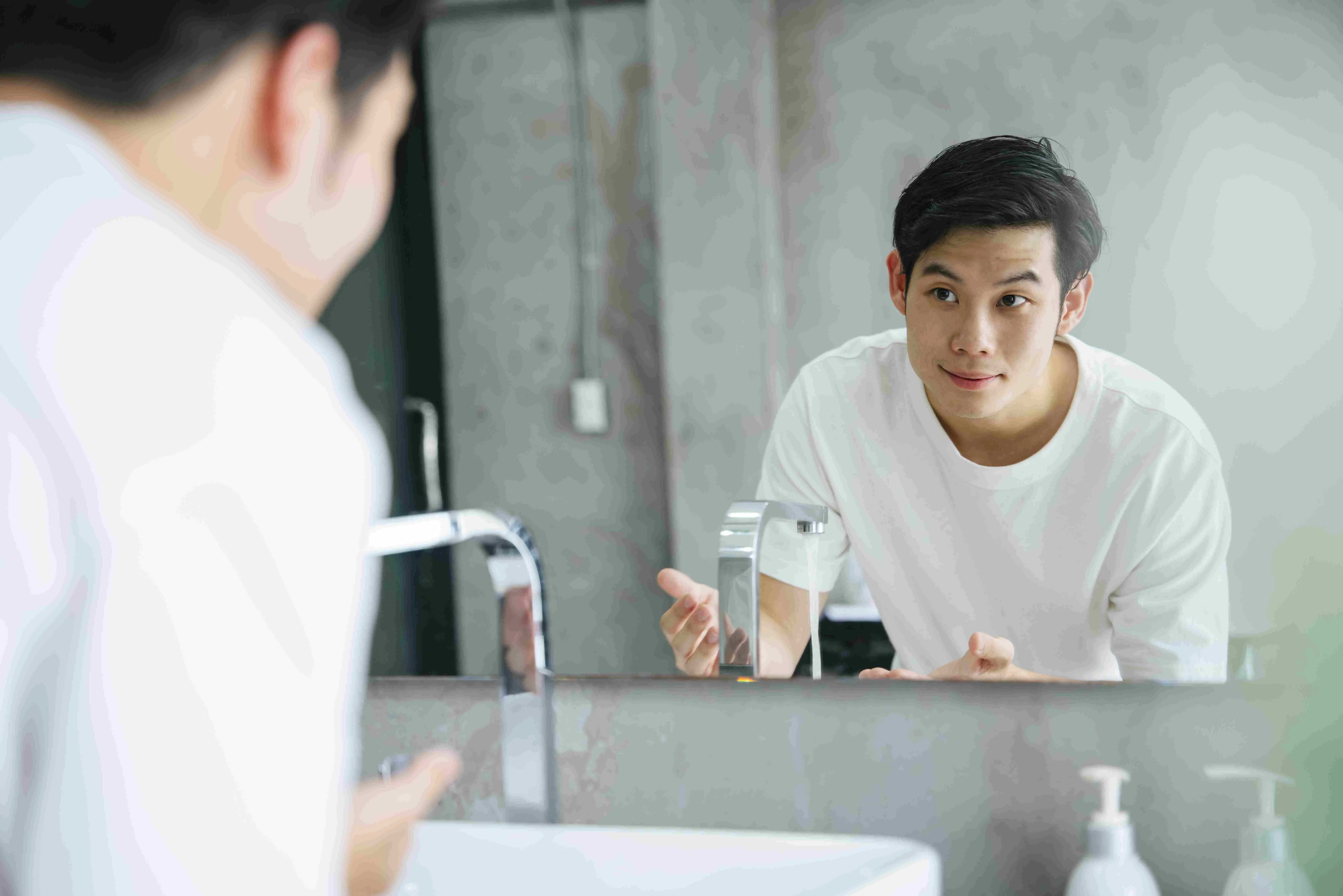 un chico limpiando su cara con aceite o colocando gel sobre el rostro