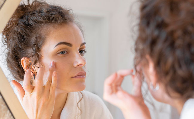 Mujer viéndose al espejo con un rostro visiblemente agotado