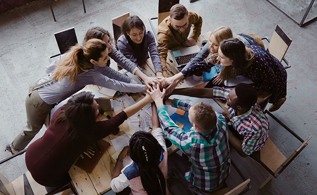 Grupo de trabajo reunido juntando la mano en muestra de celebración.