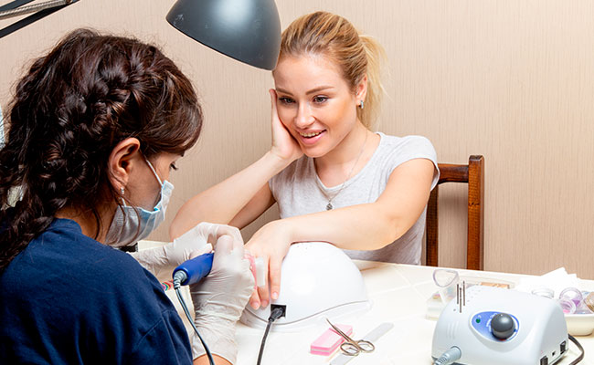 persona realizando un diseño de uñas a cliente