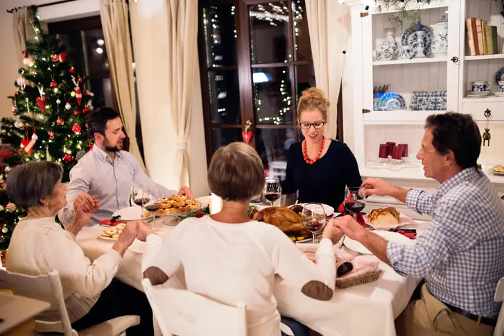 familia con las manos entrelazadas orando antes de cenar