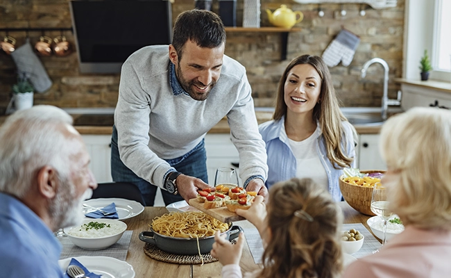 hombre sirviendo plato de comida en la mesa ante sus invitados 