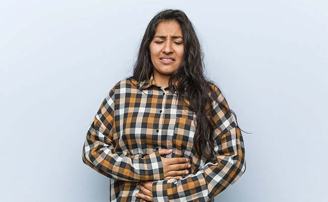 mujer sujetandose el estomago por problemas intestinales