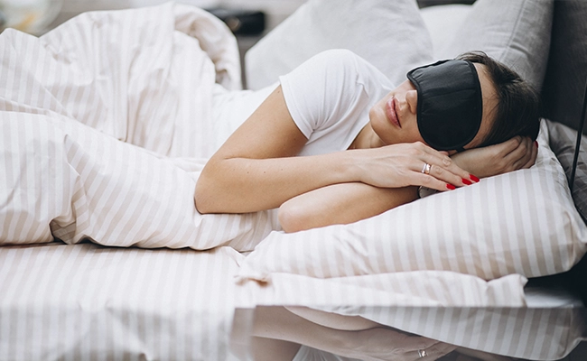 mujer durmiendo con un antifaz en los ojos y orejeras puestas