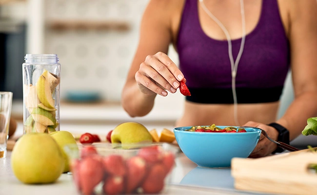 persona feliz comiendo fruta con ropa deportiva