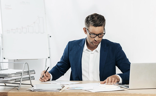 hombre completando unos papeles en su escritorio